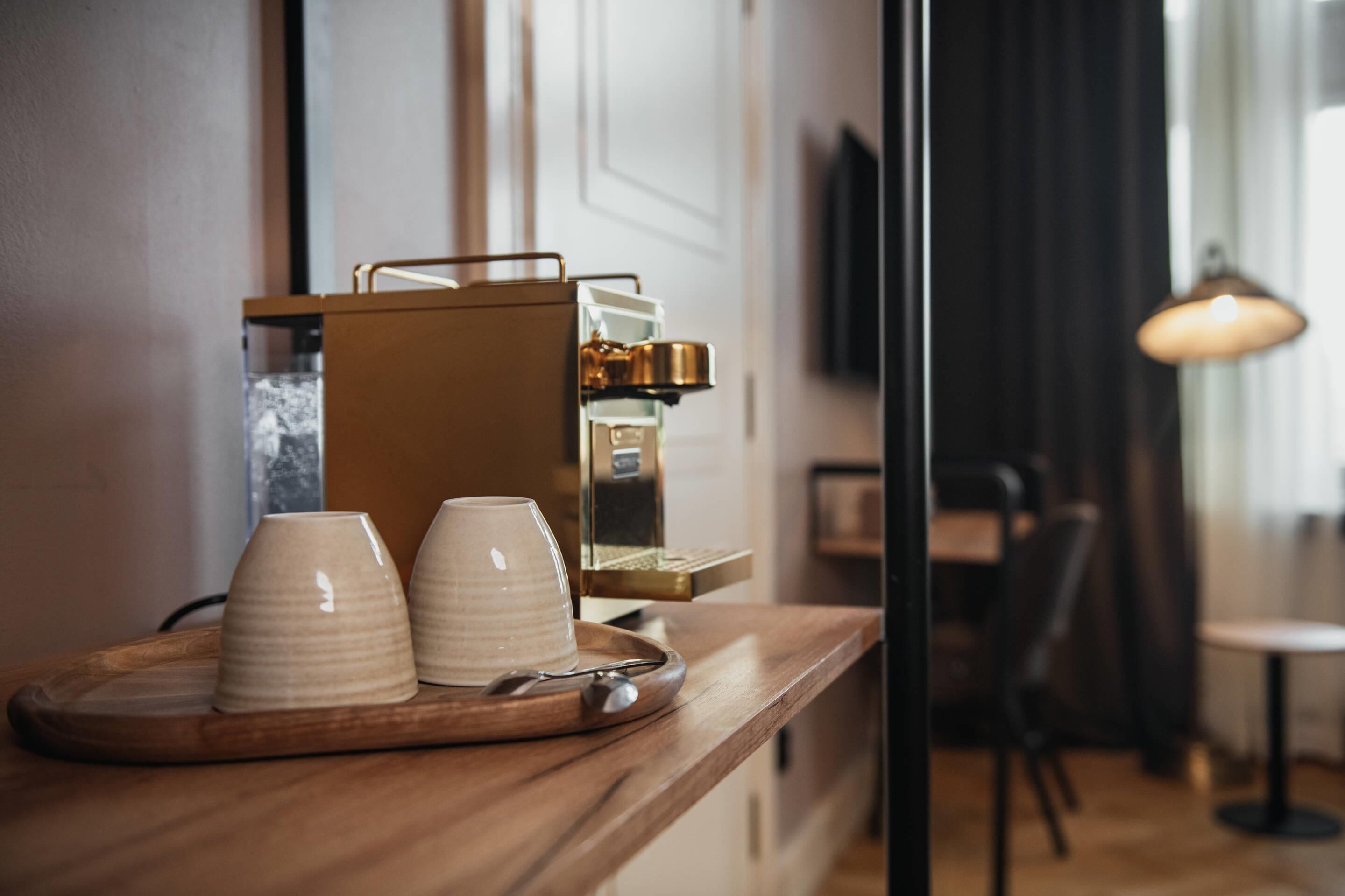 Un coin café avec deux tasses et une soucoupe, une machine à café et une lampe, le tout dans un intérieur moderne.