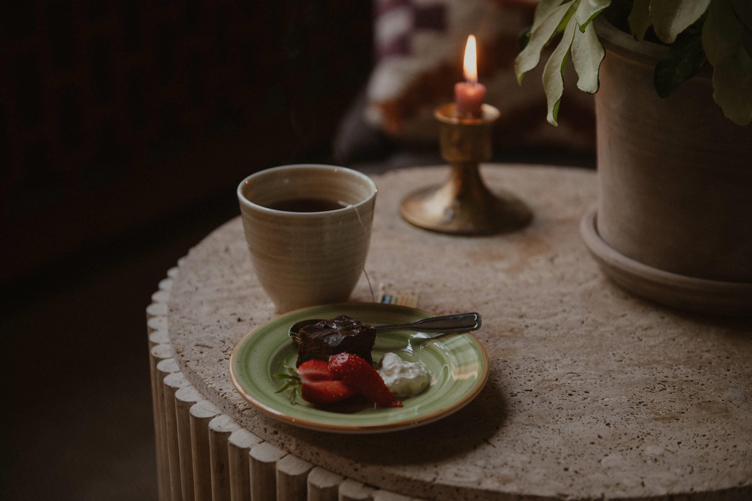 A small table with a plate of food, a cup, and a candle.