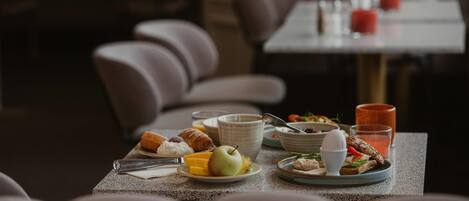 A dining table set with breakfast items including eggs, bread, and fruit, with a view of the restaurant's interior seating.
