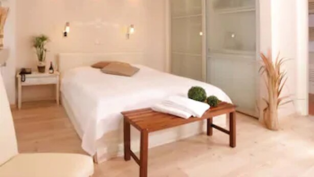 Un dormitorio con cama, mesita de noche y un banco.