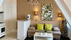 Un acogedor dormitorio tipo loft con kitchenette, comedor y sala de estar con sofá y mesa de centro.