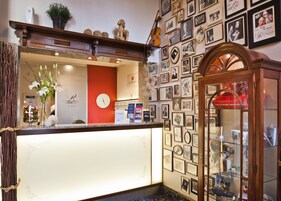 Una zona reception di un hotel con una scrivania in legno, un orologio e una parete decorata con fotografie incorniciate.