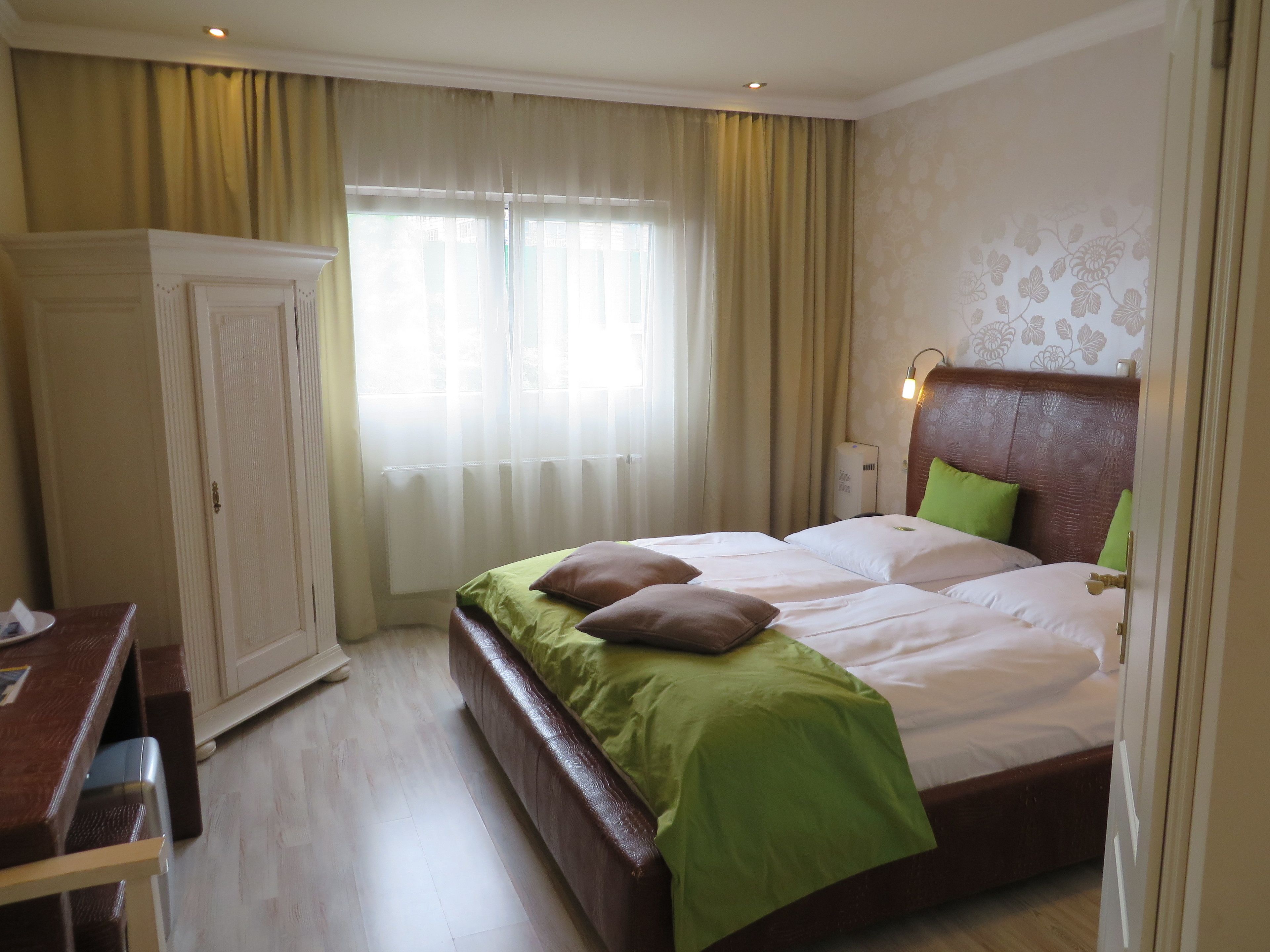 Une chambre d’hôtel avec un lit, un bureau et une armoire.