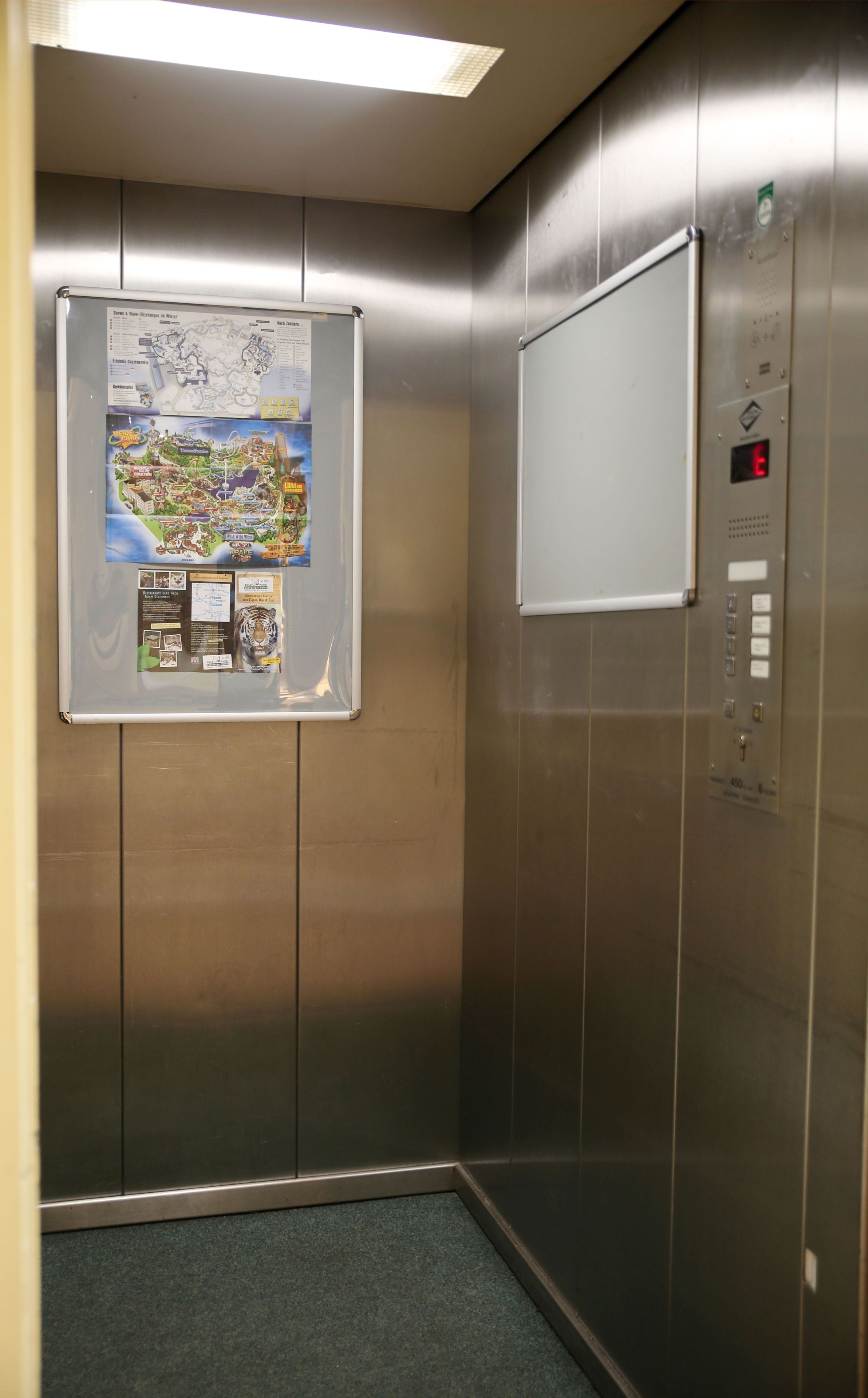 Un ascensor con un mapa y carteles informativos en la pared.