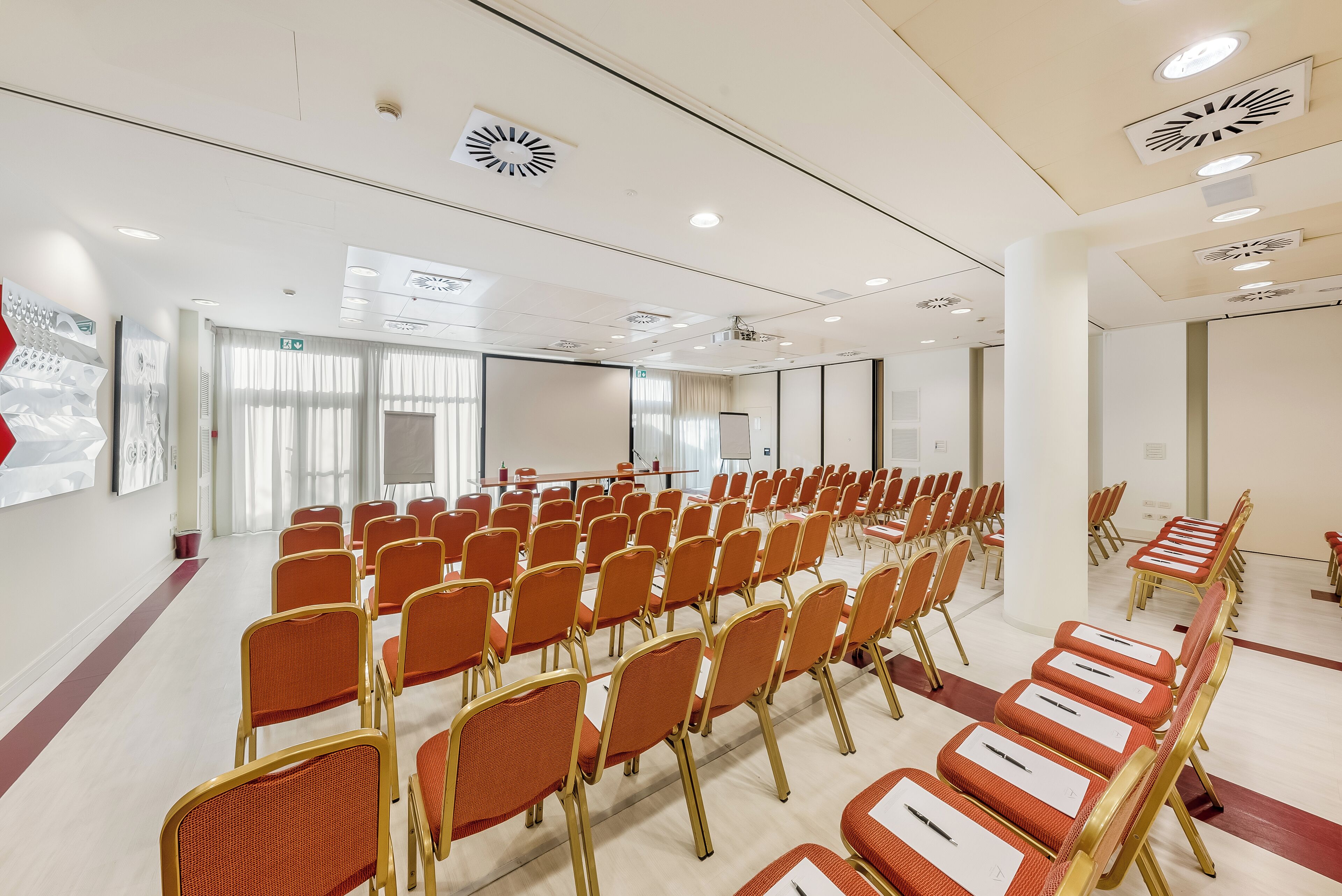 A conference room with rows of orange chairs and a whiteboard at the front.