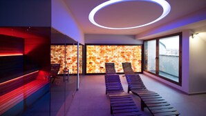 Un spa moderno con pared de madera, una lámpara circular y una fila de camillas de sol.