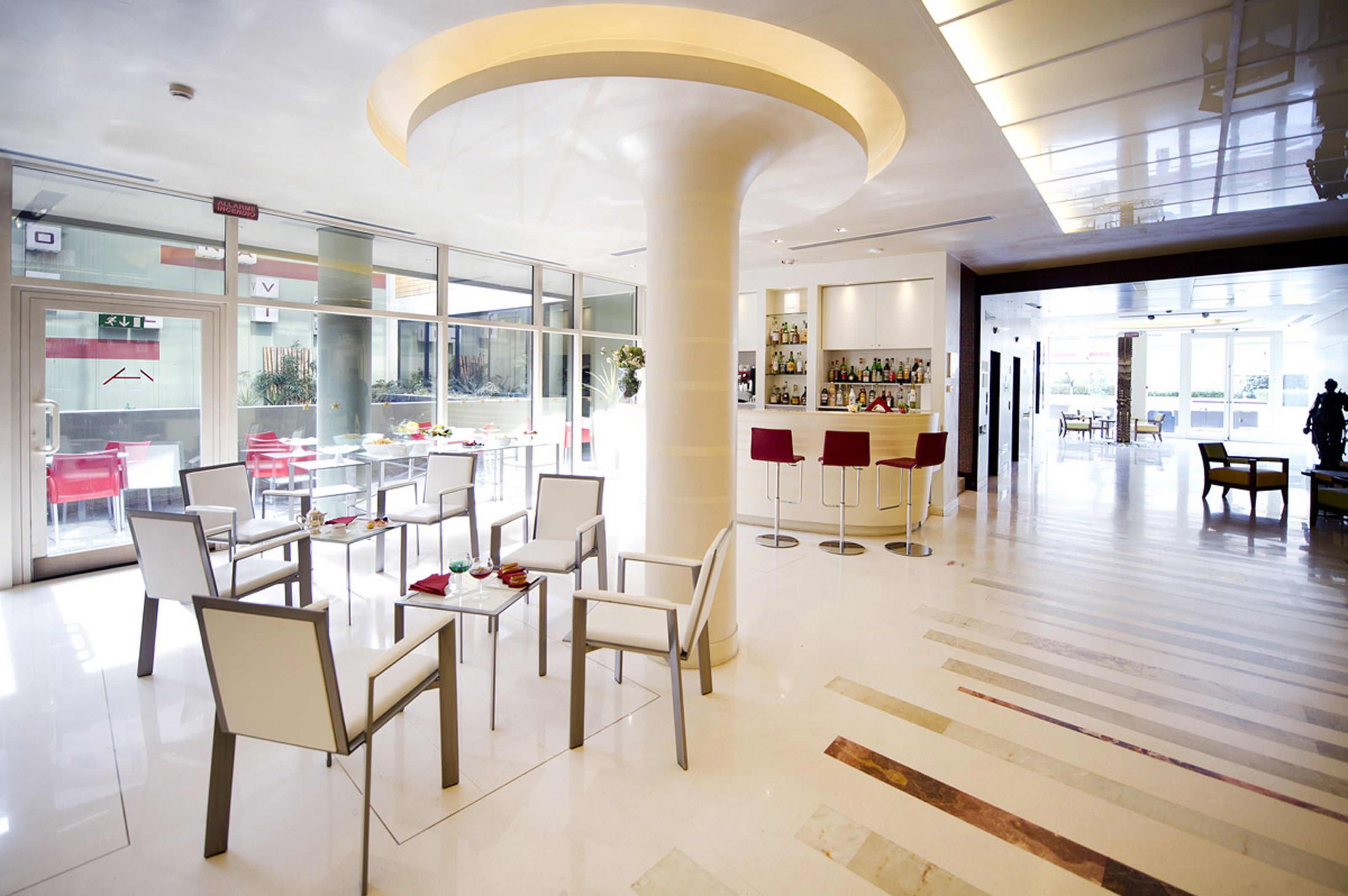 A modern hotel lobby with a seating area, a bar, and a view of the outdoors.
