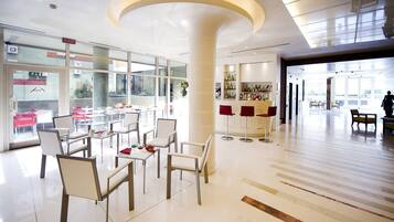 Un moderno vestíbulo de hotel con zona de estar, un bar y vistas al exterior.