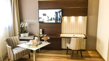 Une chambre d’hôtel dotée d’un coin repas comprenant une table, des chaises et un téléviseur fixé au mur.