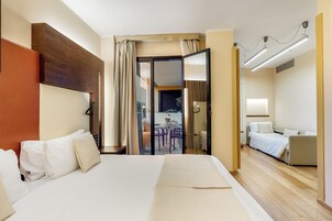 A hotel room with a large bed, a desk, and a balcony with outdoor seating.