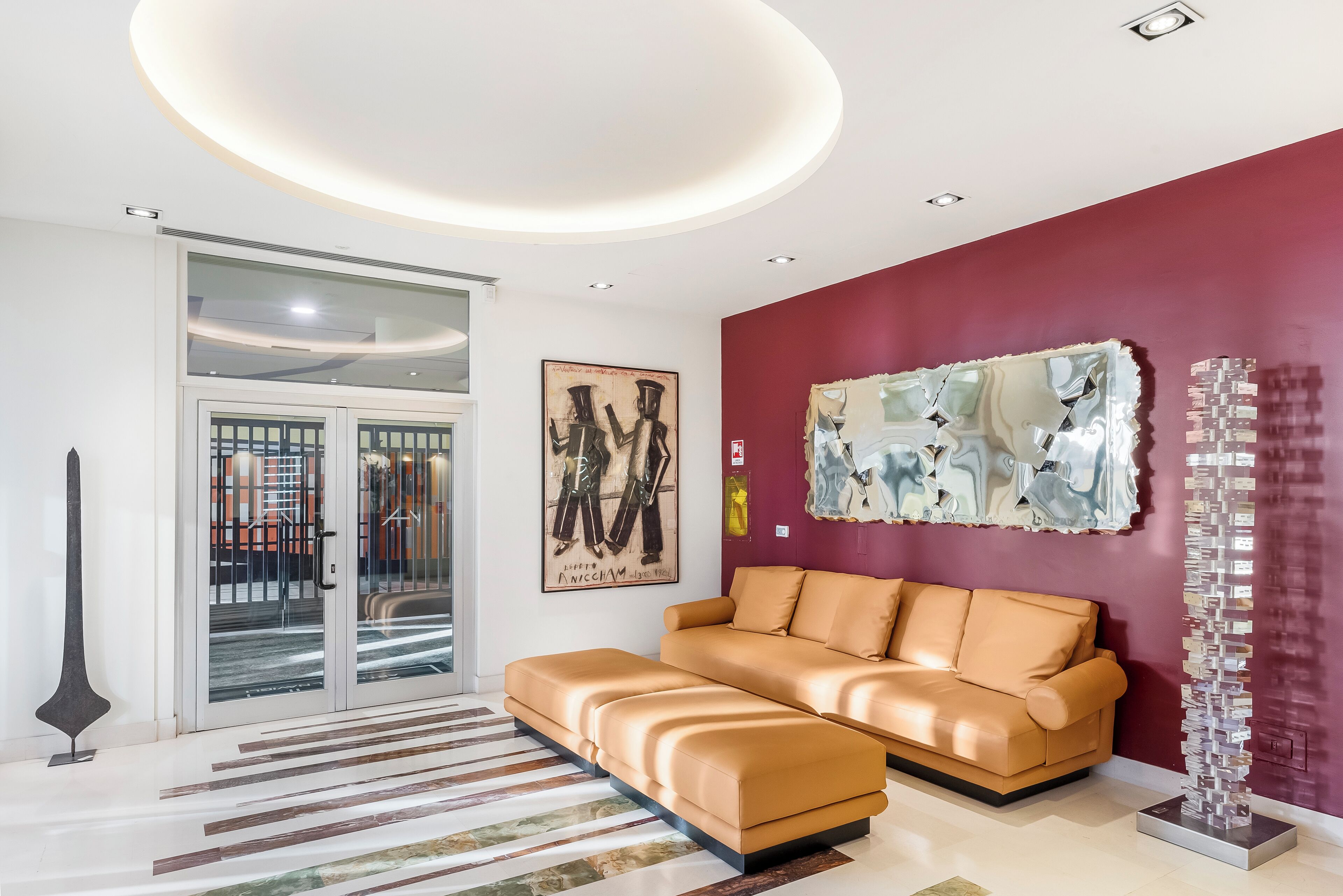 A modern living room with a sofa, abstract art, and a unique sculpture.