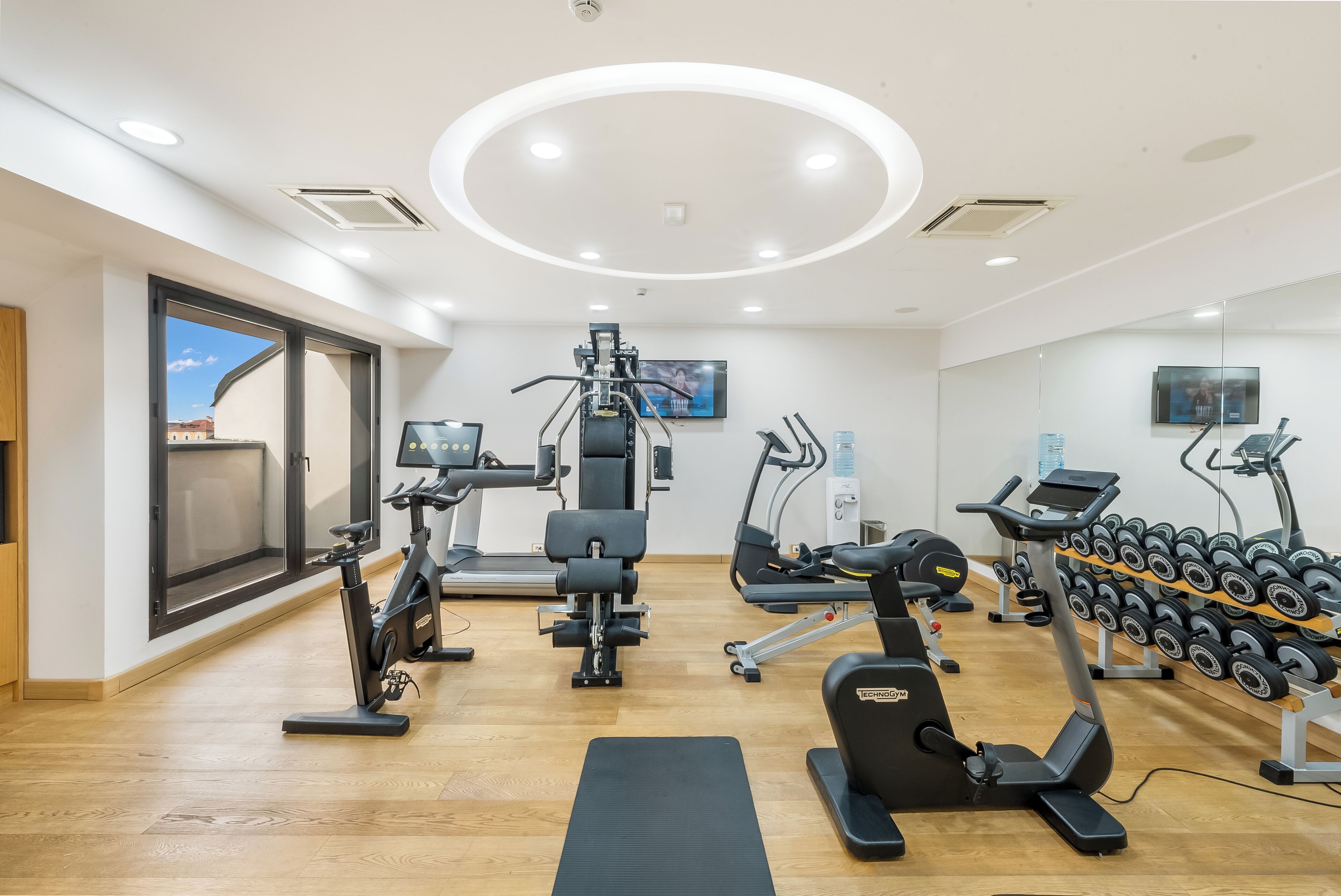 Uma academia moderna com equipamentos de cardio, aparelhos de musculação e halteres.