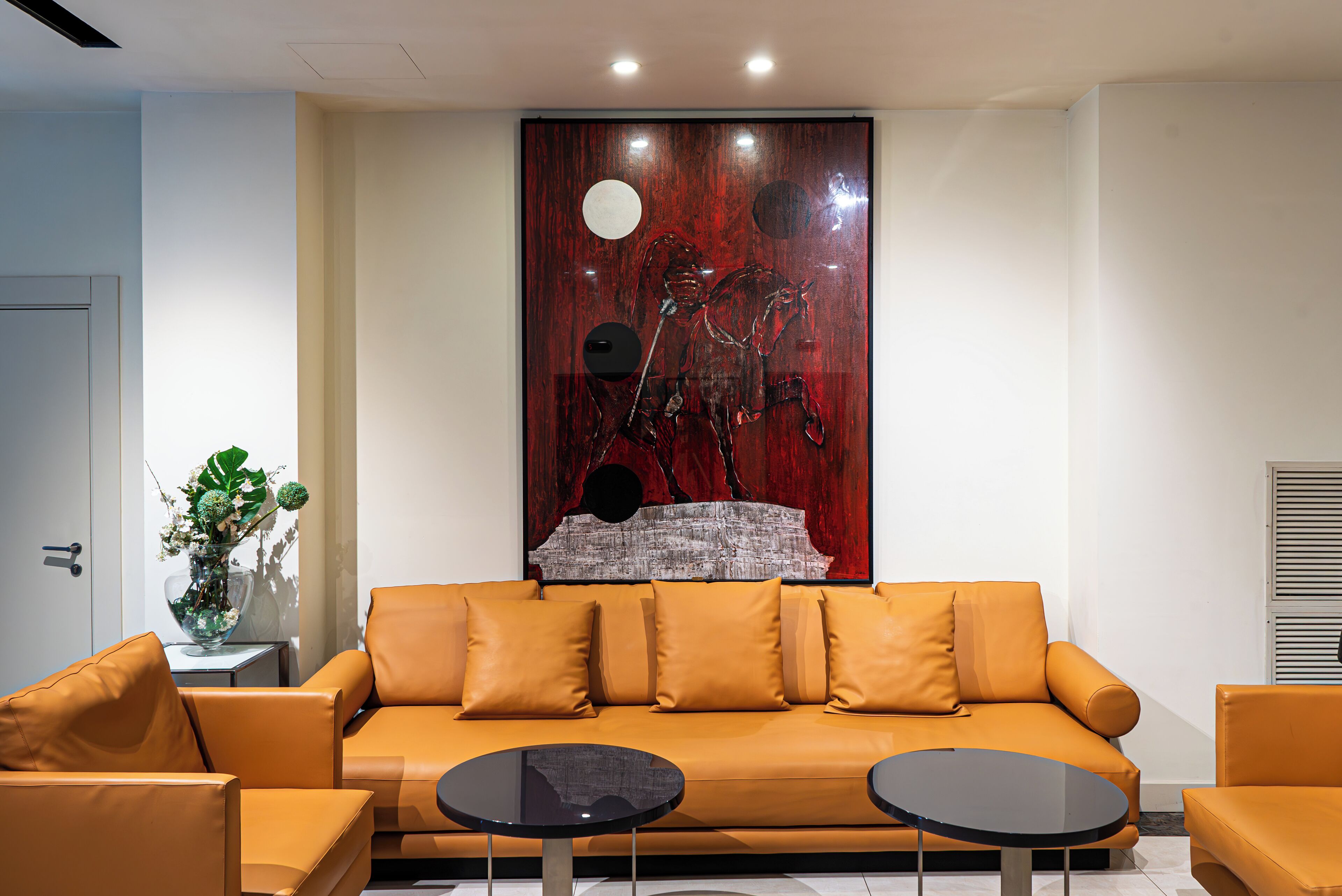 A modern living room with a sofa, two side tables, and a decorative wall piece.