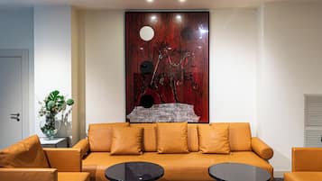 A modern living room with a sofa, two side tables, and a decorative wall piece.