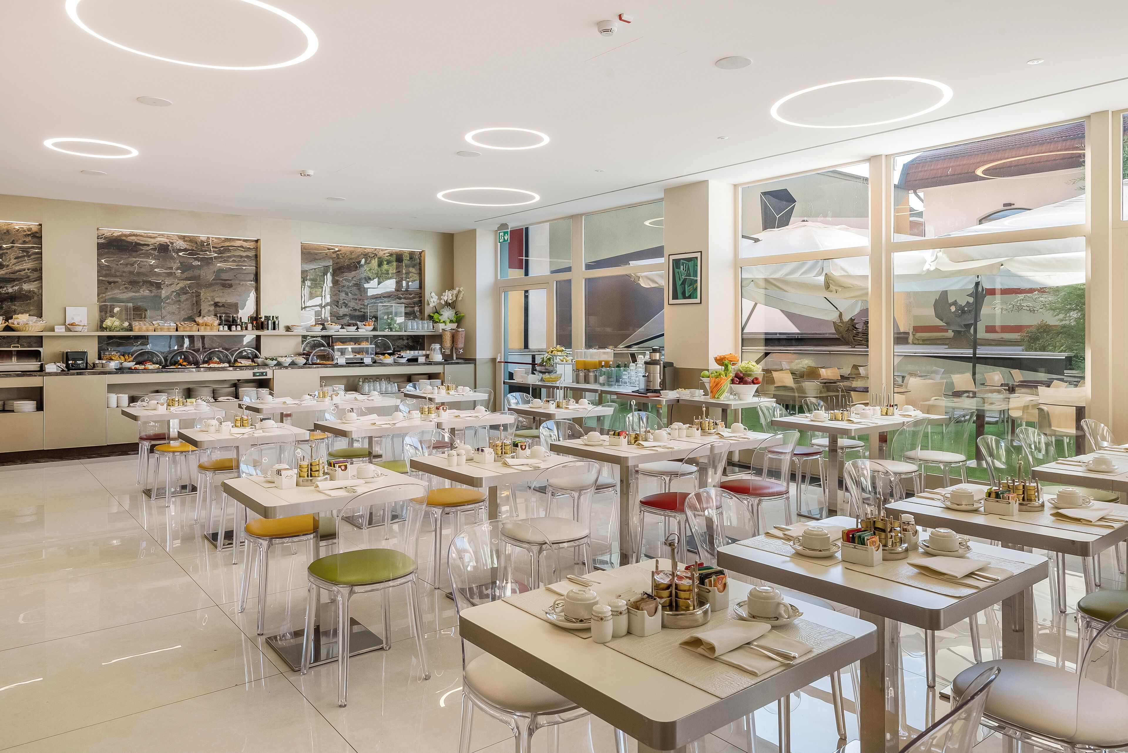 Un restaurante moderno con sillas de vidrio transparente, mesas blancas y un ambiente luminoso.