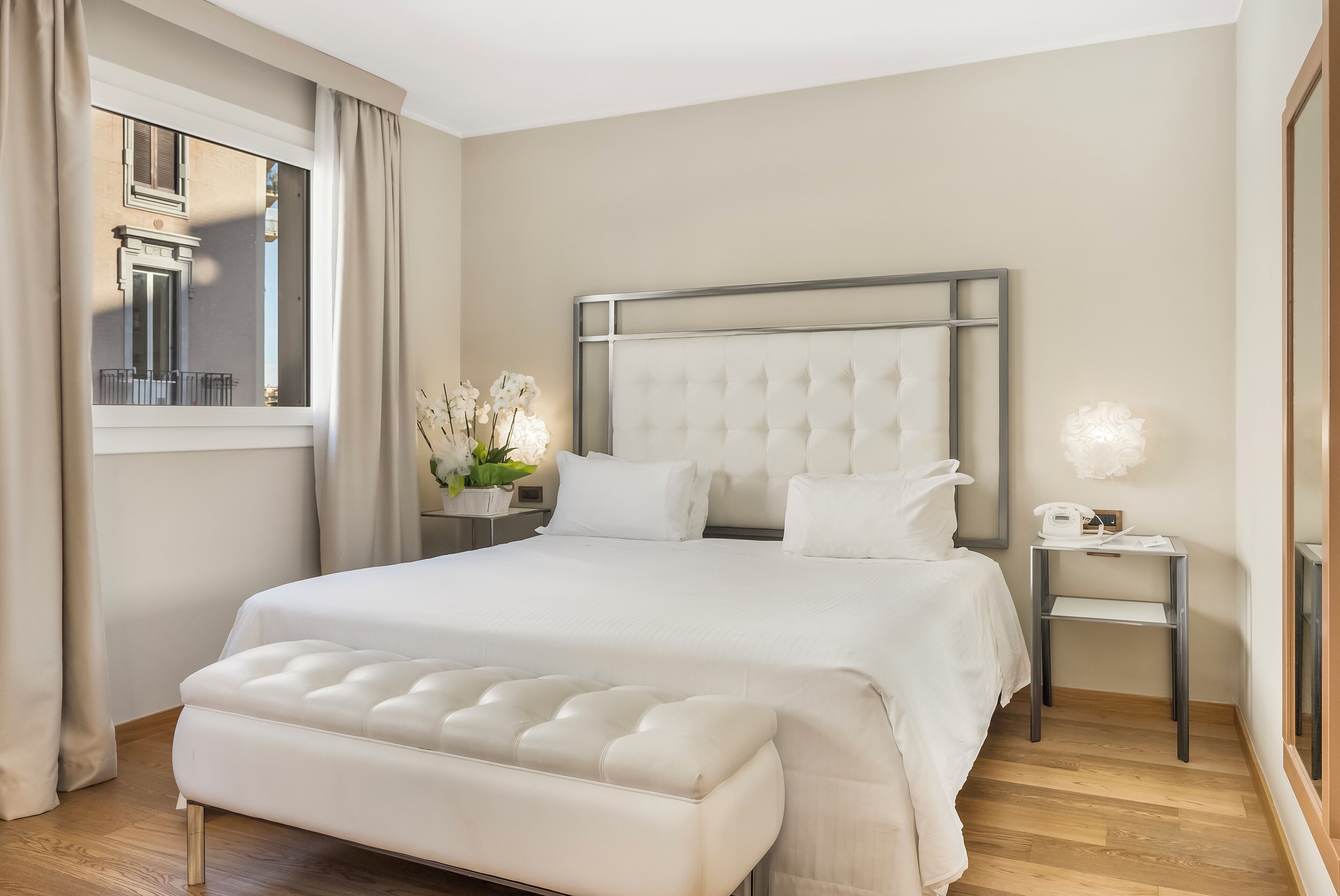Un dormitorio moderno con una cama grande, una mesita de noche y una ventana con cortinas.