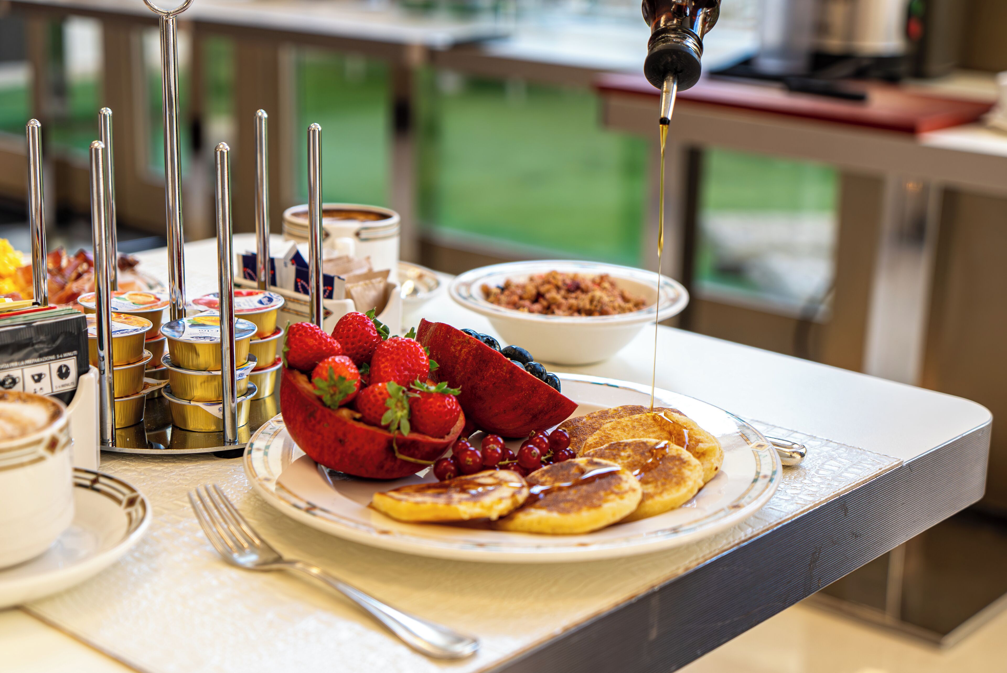 A breakfast buffet with pancakes, strawberries, blueberries, and a variety of other breakfast items.