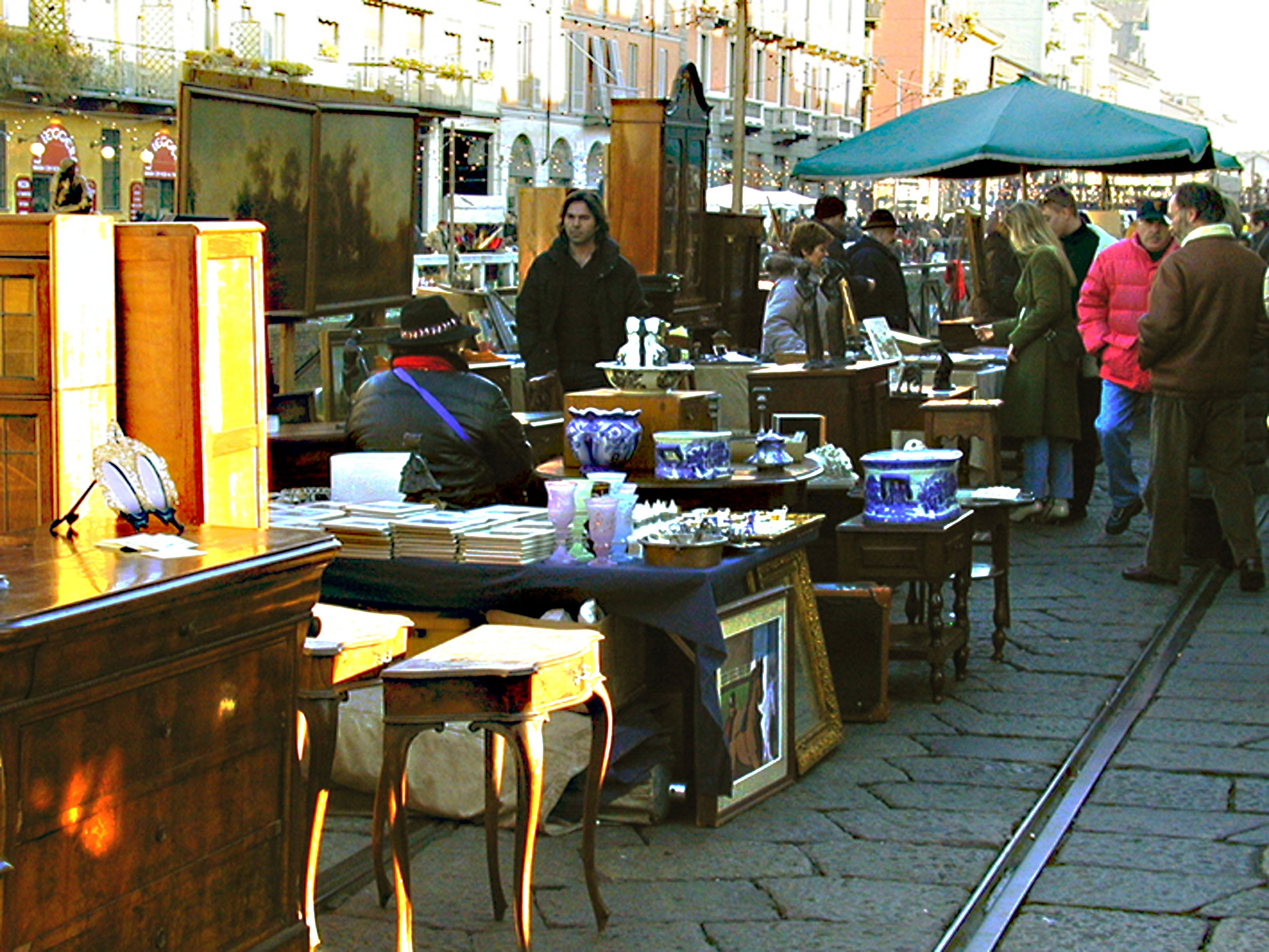 A market stall with various items on display, including ceramics and framed pictures.