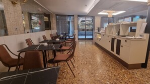 Un restaurante con mesas y sillas de encimera de mármol, suelo de terrazo y una barra con la carta.