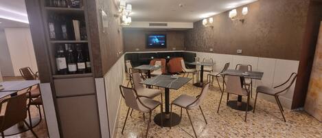 Un restaurant doté d’un bar, de tables, de chaises et d’un écran de télévision.