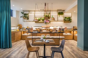 A modern breakfast bar with a wooden table, two chairs, and a variety of breakfast items. - Occidental Vigo (Vigo)