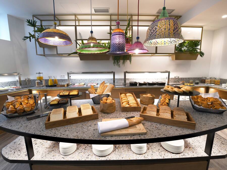 A buffet setup with various breads, pastries, and fruits.