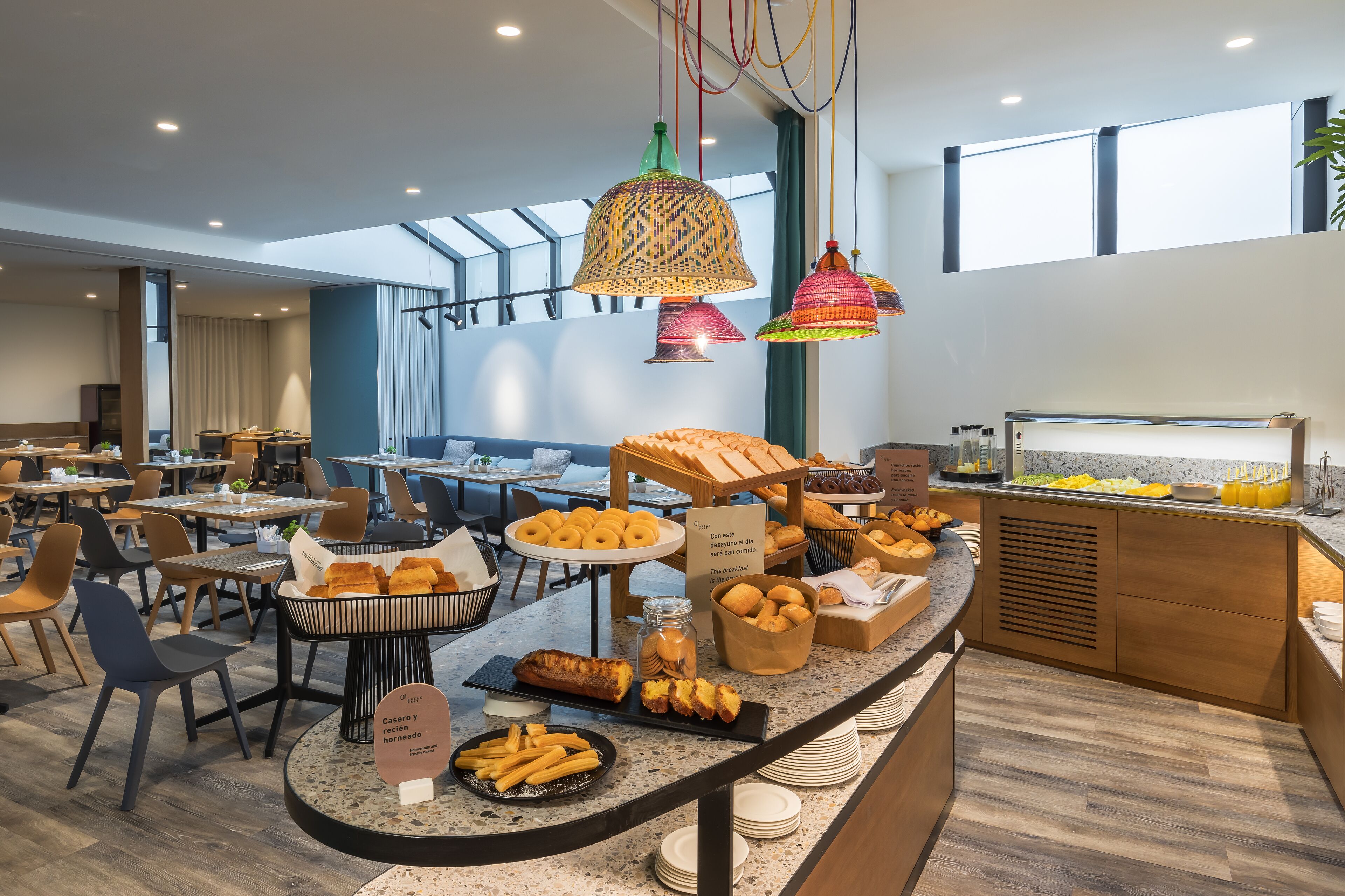 Zona de dinar d'un hotel modern amb un sistema de menjar a gran bufet, incloent pa, pastissos i diverses opcions per esmorzar.