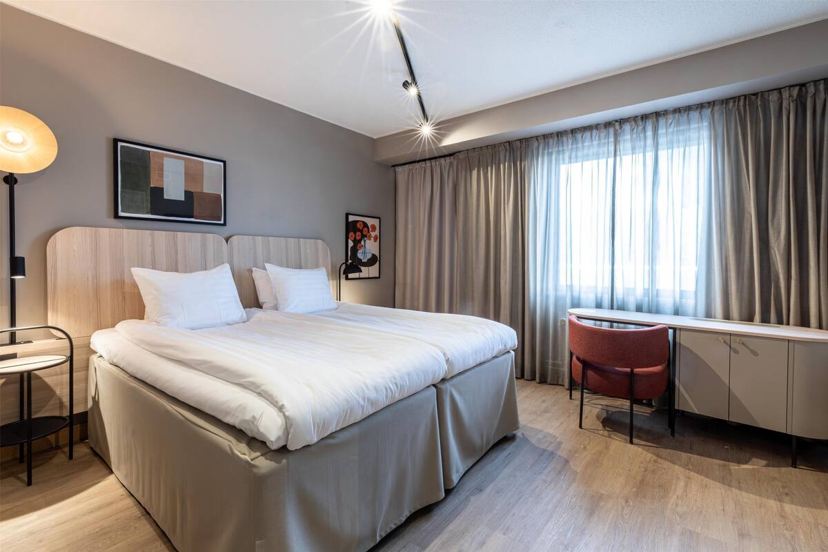 Une chambre d’hôtel moderne, dotée d’un grand lit, d’un bureau et d’une chaise.