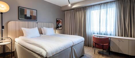 Una habitación de hotel moderna con una cama grande, un escritorio y una silla.