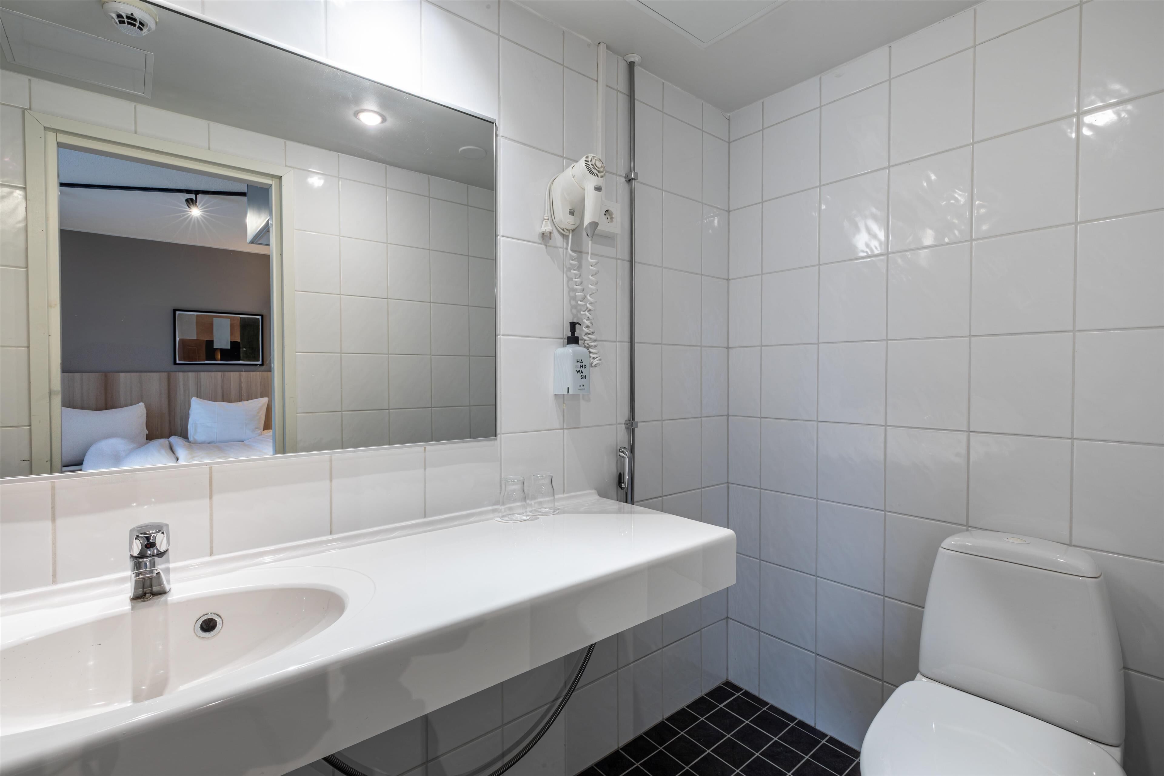 A modern bathroom with a white sink, mirror, and toilet.