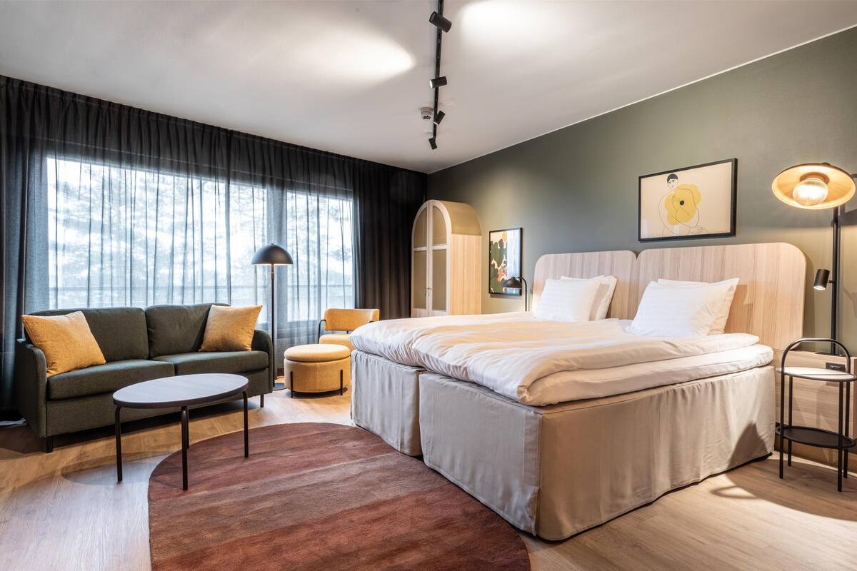 Une chambre d’hôtel moderne avec un grand lit, un canapé, une petite table et une chaise.