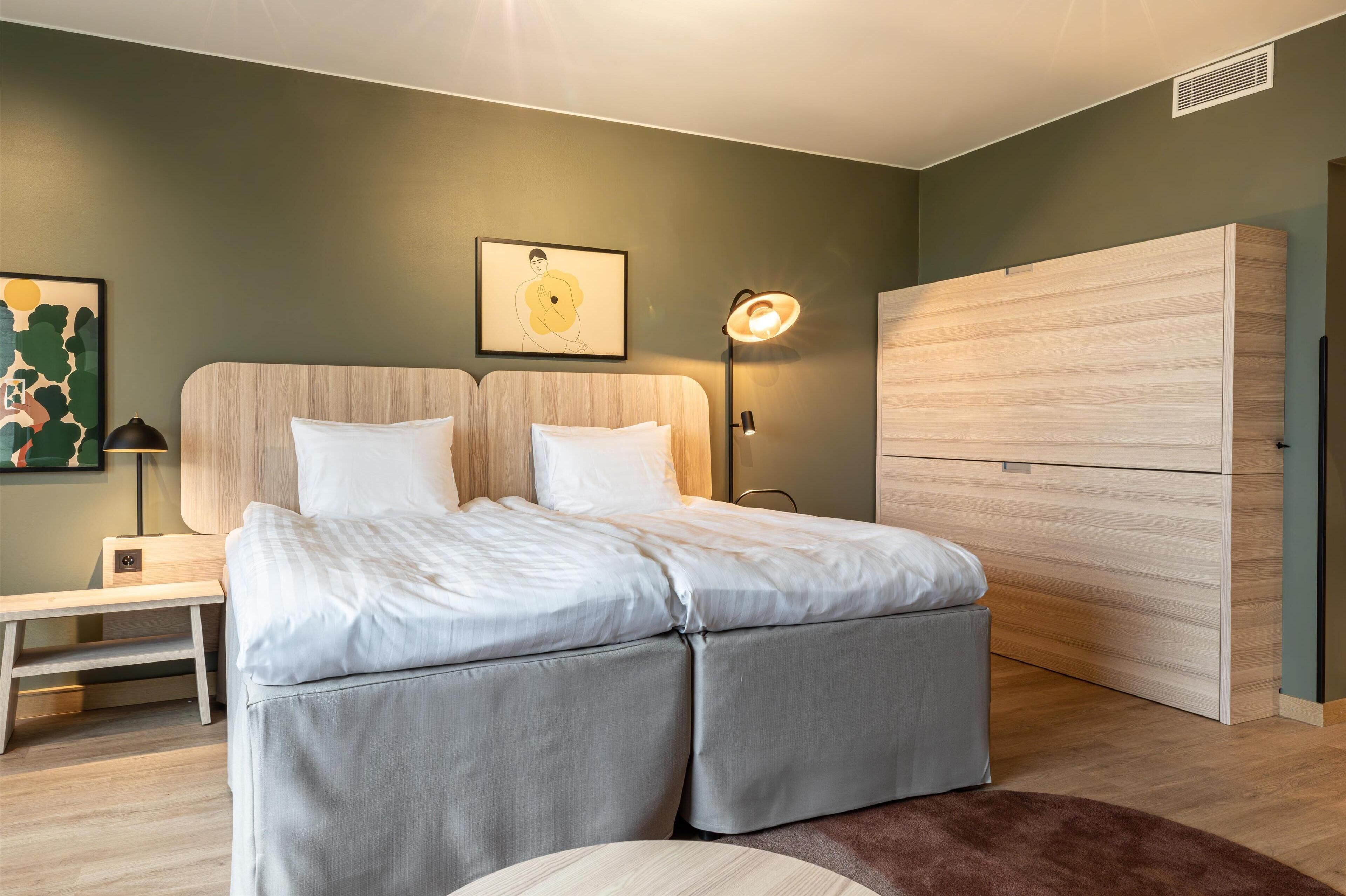 A modern bedroom with a bed, bedside table, lamp, and wardrobe.