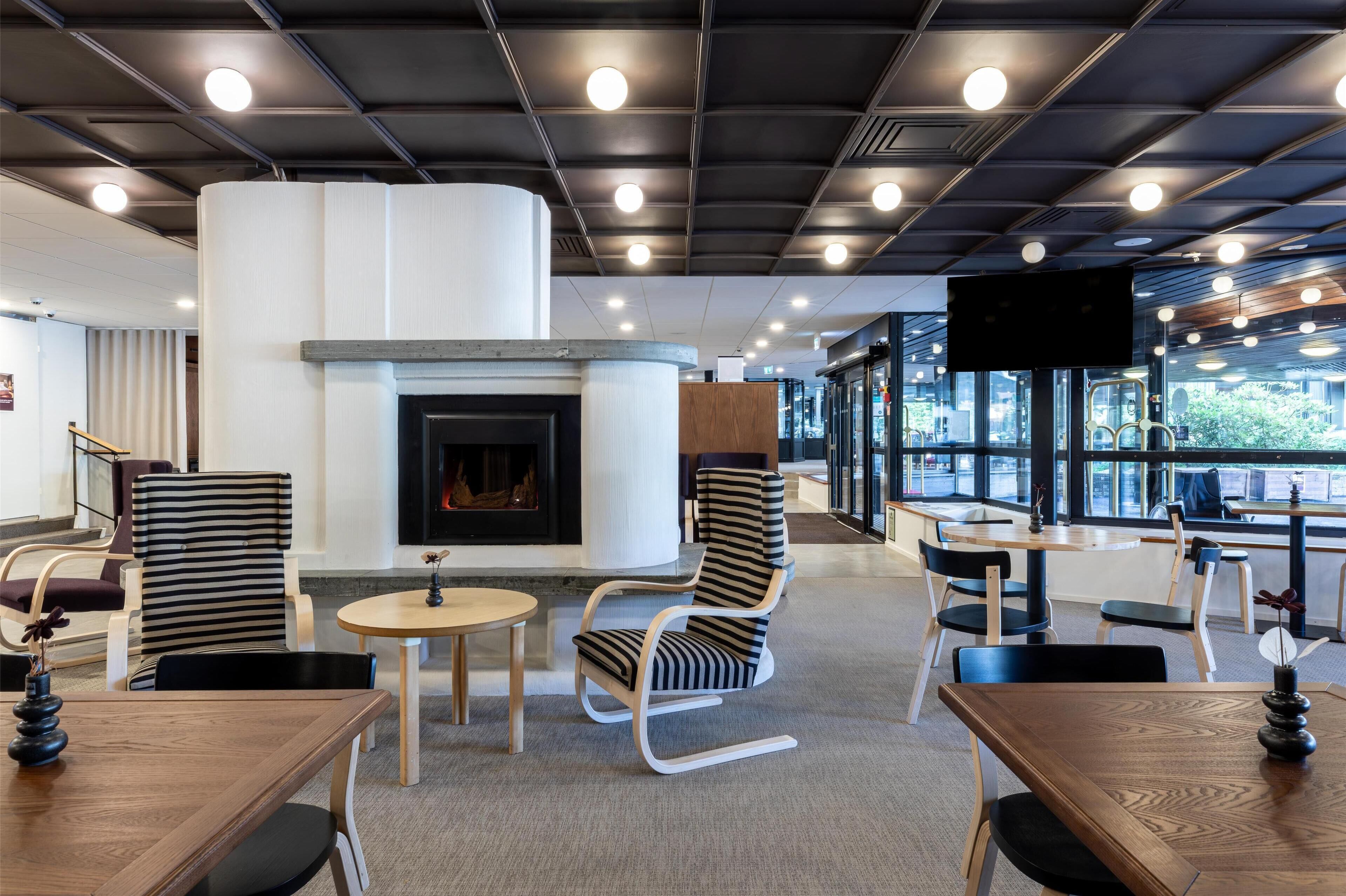 A modern lounge area with a fireplace, seating, and large windows.