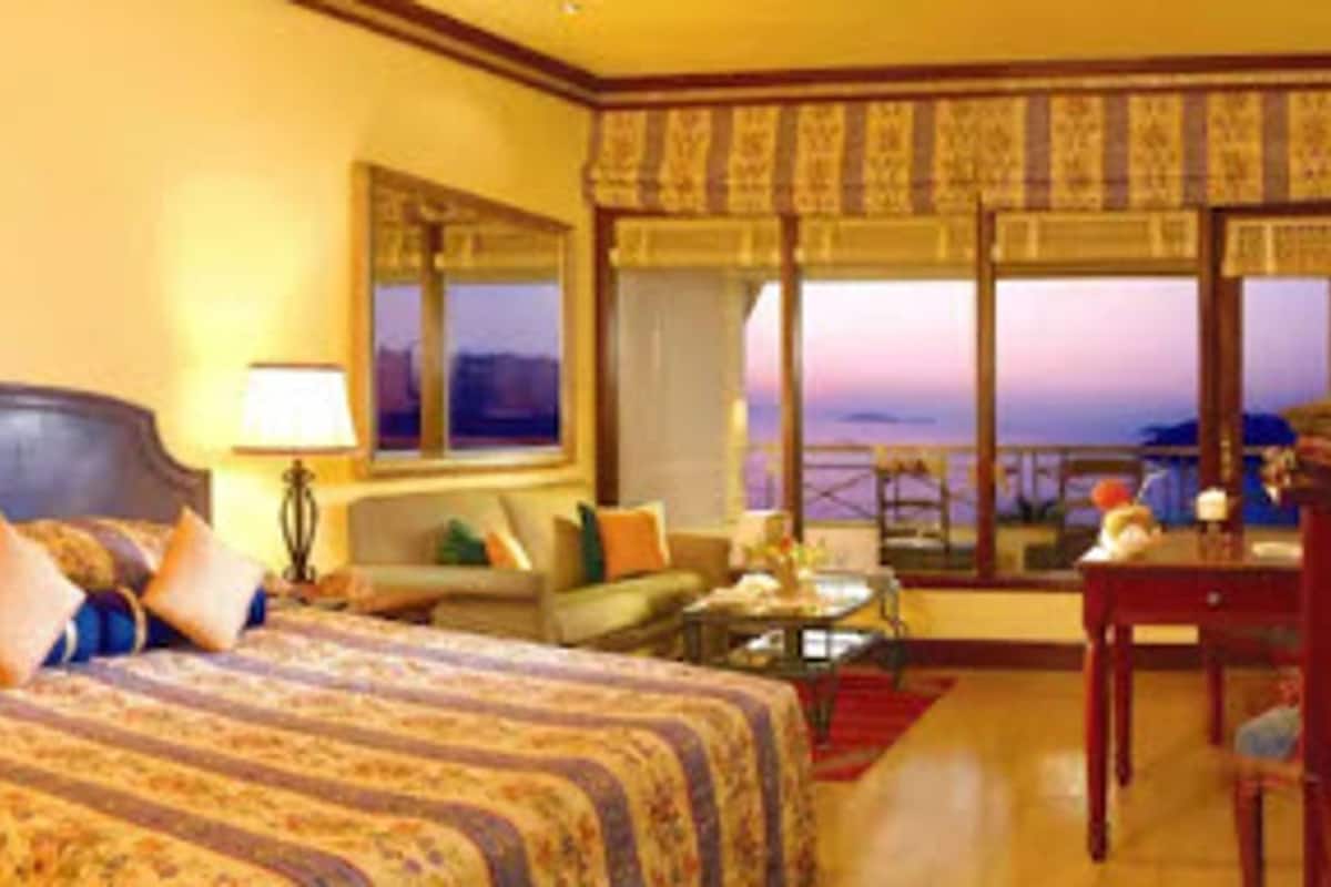 A hotel room with a large bed, a sofa, a desk, and a view of the ocean.