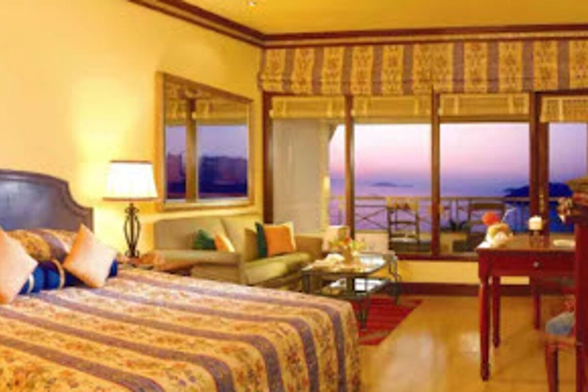 Habitación de hotel con una cama grande, un sofá, un escritorio y vista al océano.