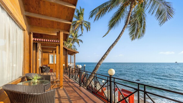 A wooden deck with wicker furniture overlooking the sea. - Bogmallo Beach Resort (Marmagao)