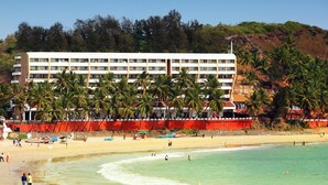 A beachfront hotel with multiple floors, palm trees, and a sandy beach. - Bogmallo Beach Resort (Marmagao)