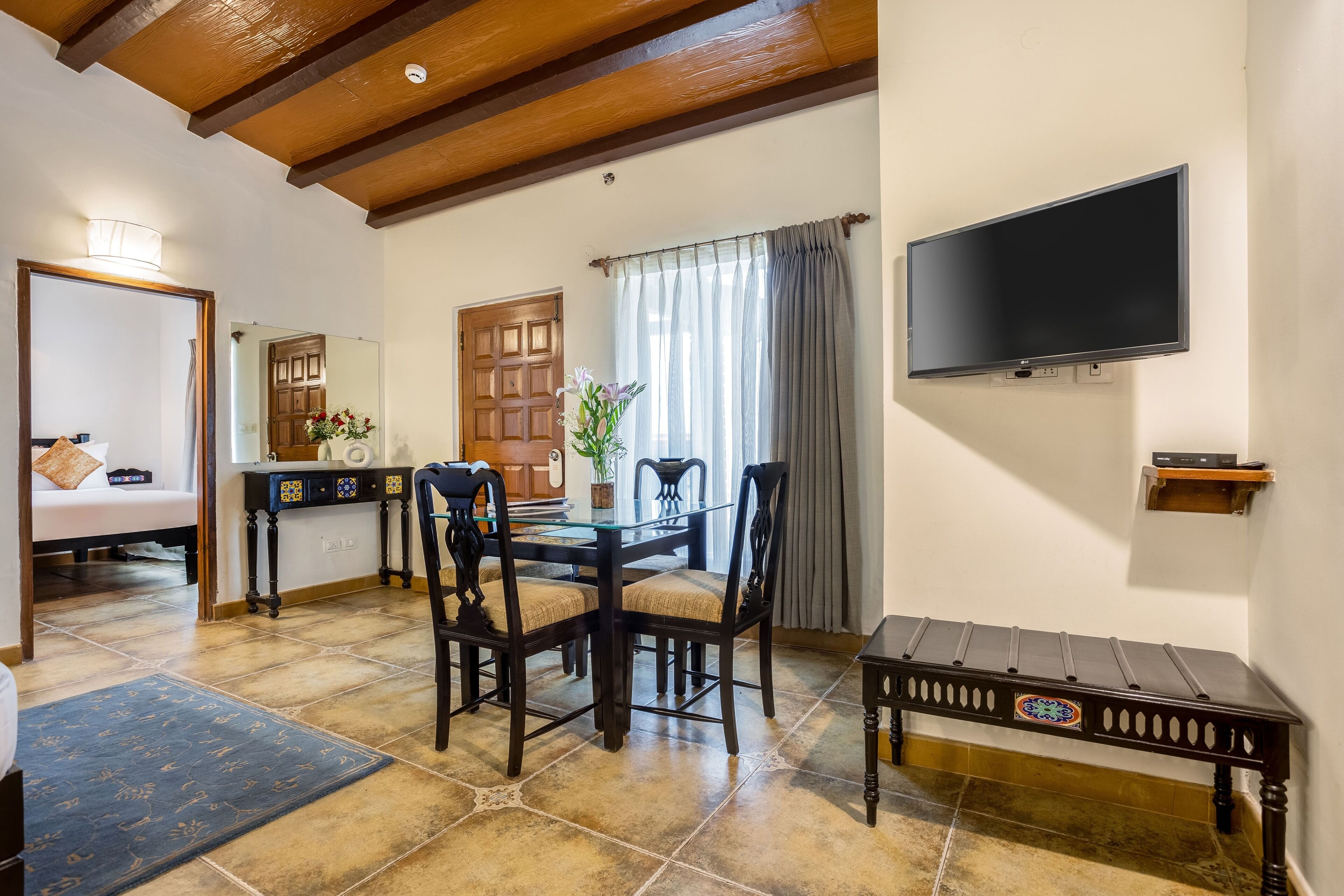 A dining area with a wooden table, chairs, and a television mounted on the wall.