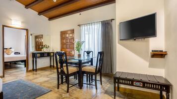 A dining area with a wooden table, chairs, and a television mounted on the wall.