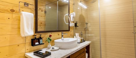 A modern bathroom with a wooden interior, a large mirror, a white sink, and a glass shower enclosure.