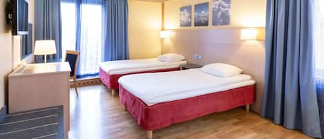 A hotel room with two beds, a desk, a chair, and a TV.