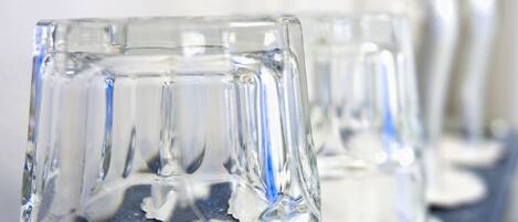 A row of clear glass tumblers on a blue countertop.