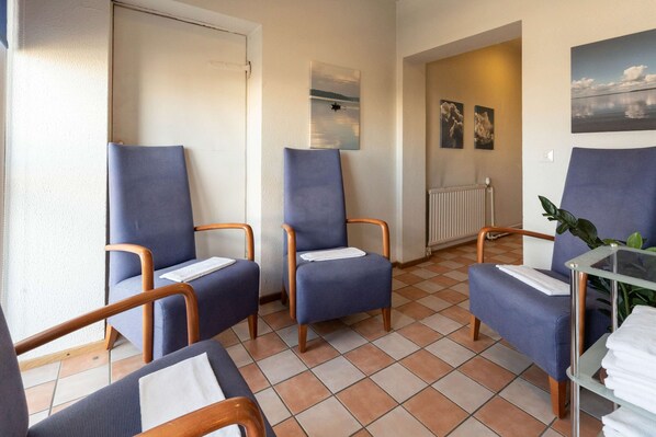 Une pièce avec trois chaises bleues, une table en verre avec des serviettes et un radiateur.