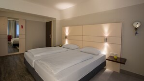 Habitación de hotel moderna con una cama grande, mesitas de noche, un espejo y una lámpara fijada a la pared.
