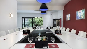Un salón de conferencias con mesas blancas, manteles individuales rojos y un centro de mesa con Fitz-Kola.