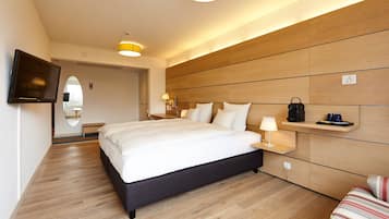 Een moderne hotelkamer met een groot bed, nachtkastjes, een televisie en een houten hoofdeinde.