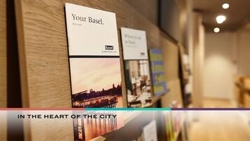 Un espositore per brochure con un cartello di benvenuto e un'immagine del panorama urbano.