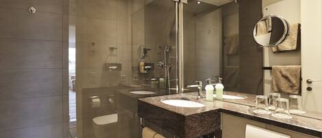 A modern bathroom with a glass shower enclosure, dual sinks, and a large mirror.