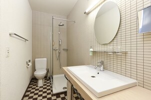 Un baño con lavamanos blanco, inodoro, ducha y espejo.
