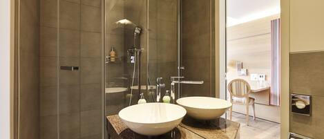 A modern bathroom with a glass-enclosed shower, two sinks, and a mirror.